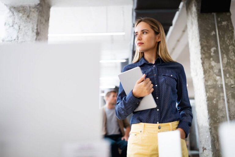 Coördinator Shared Service Center loopt met tablet door het kantoor van Quinnect